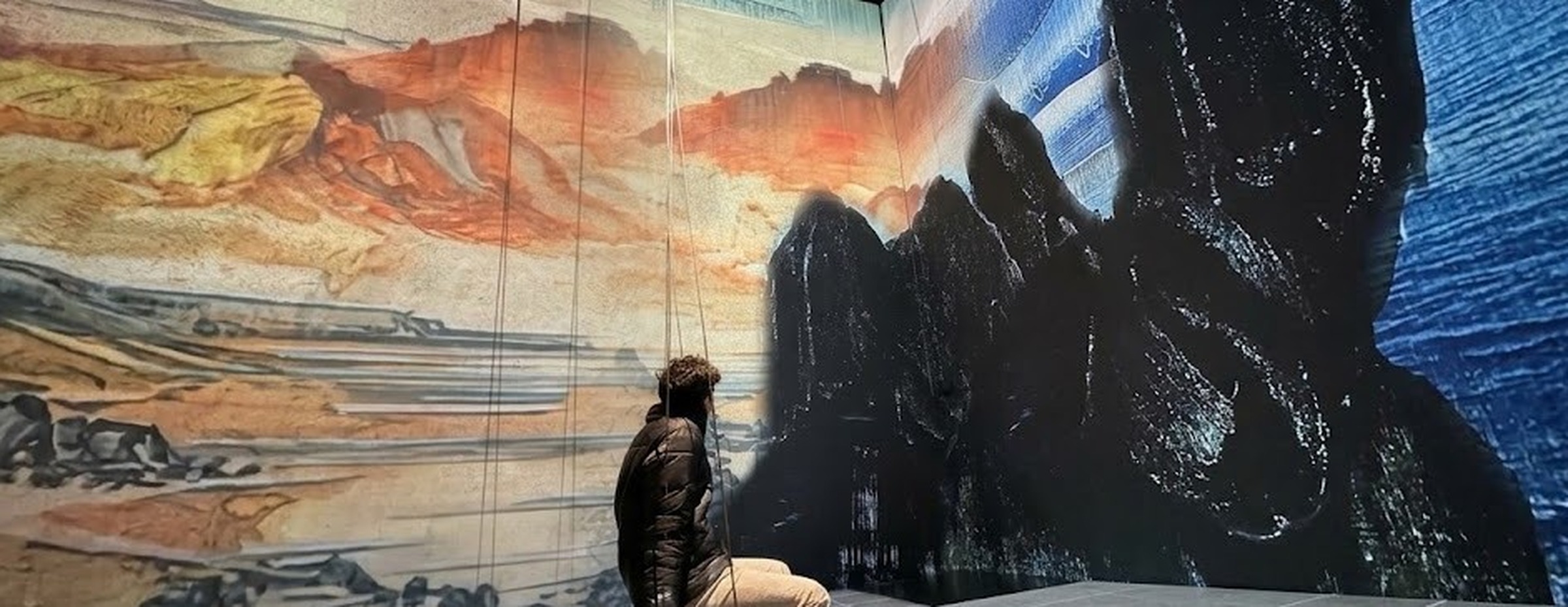 Sitting on a swing inside an immersive art installation, facing a vast mural, in quiet thought